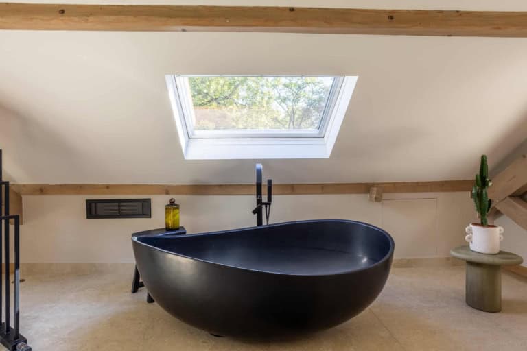 Baignoire îlot noire sous une fenêtre de toit