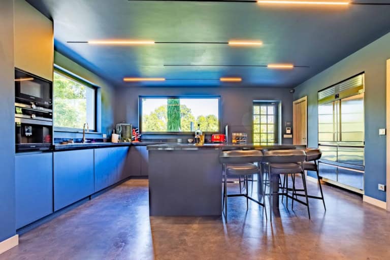 Cuisine bleue avec îlot central et tabourets dans une propriété près de Deauville