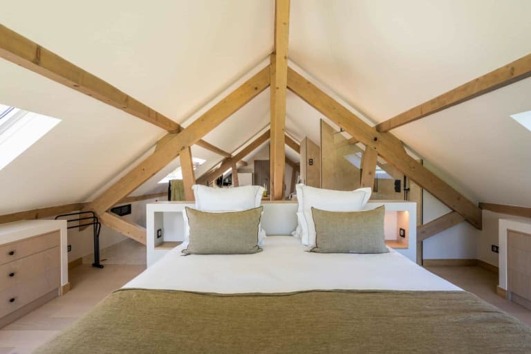 Suite sous les combles avec grand lit et charpente apparente