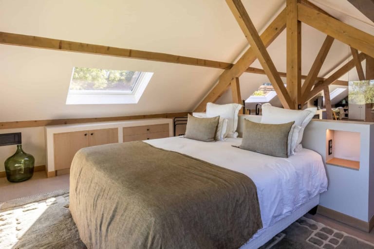 Chambre mansardée avec charpente en bois et lit double