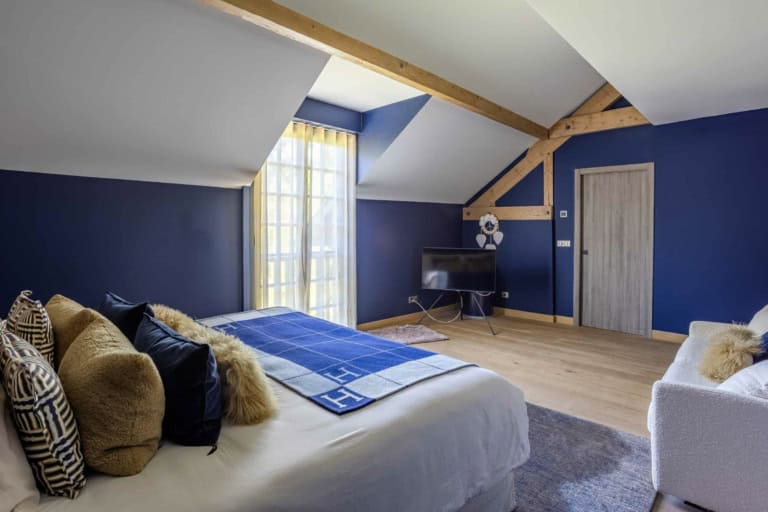 Grand lit dans une chambre sous combles aux murs bleus