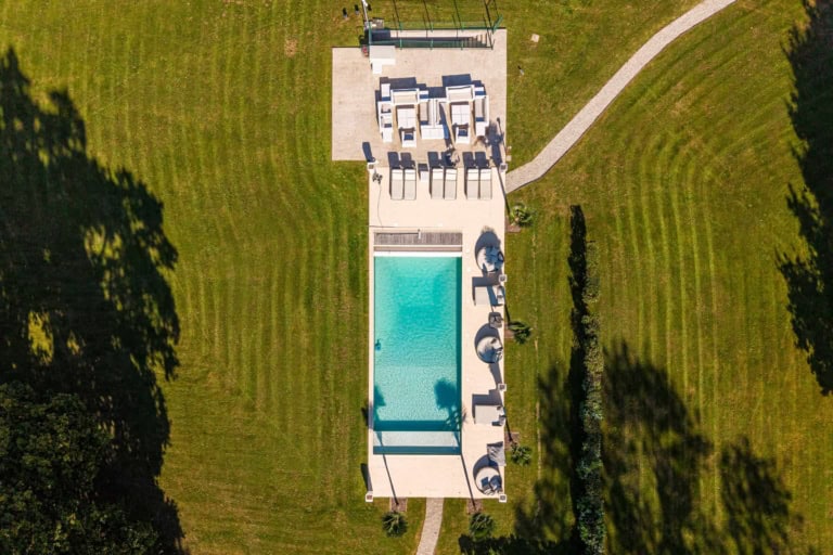 Piscine et sa terrasse vues par drone dans le jardin d'une demeure normande