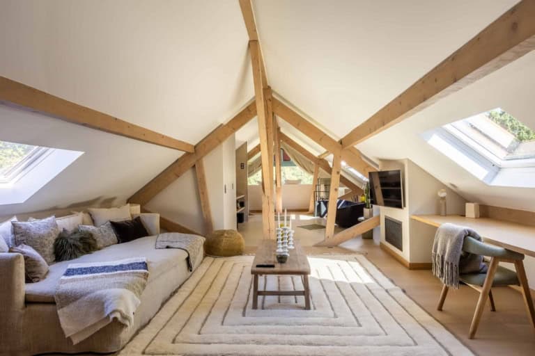 Salon sous les combles avec charpente en bois et fenêtres de toit
