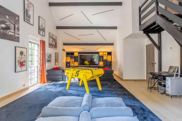 Salle de jeux avec baby-foot jaune et grand écran dans une maison de caractère