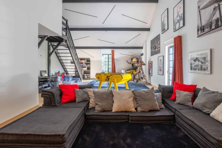 Salle de jeux avec grand canapé et mezzanine dans une maison d'exception du Calvados