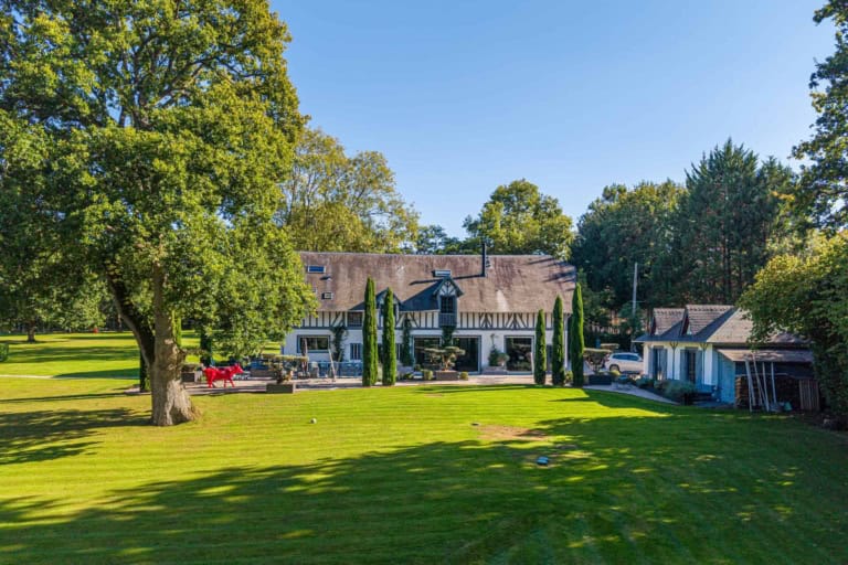 Maison normande et son grand jardin sous un ciel bleu, près de Deauville