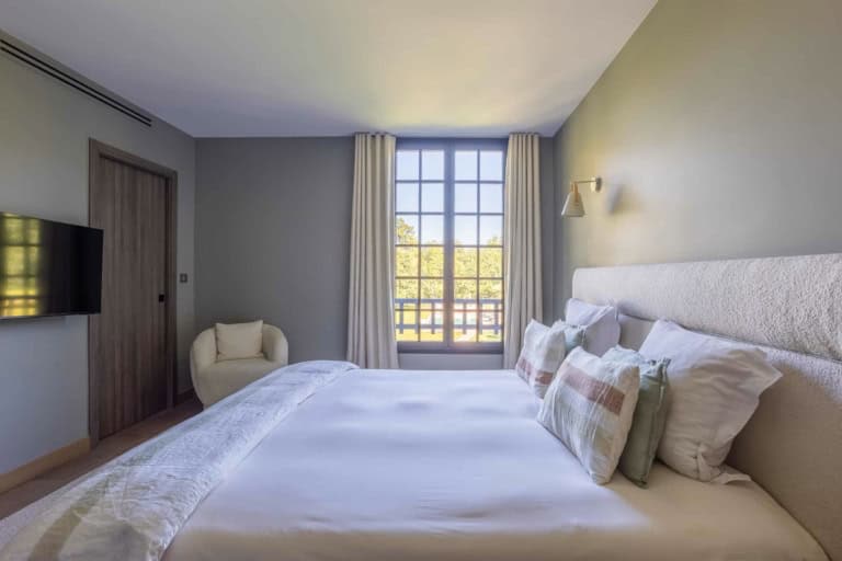 Suite aux tons gris avec grand lit et fenêtres sur le parc